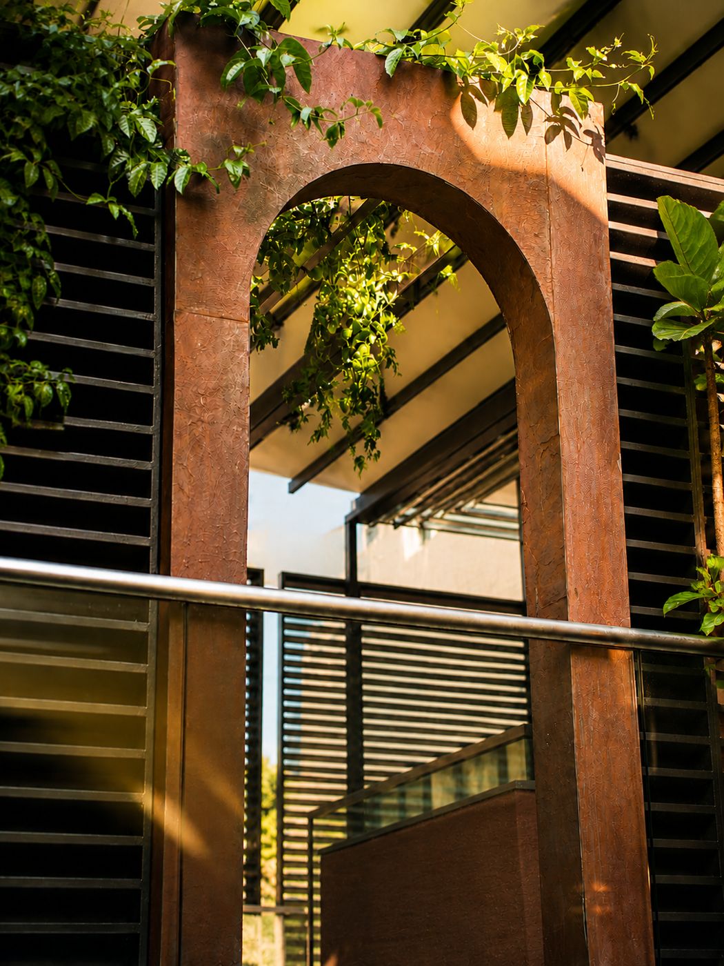 The terracotta arch at the 3al Awwal entrance, with climbing plants and dark louvres